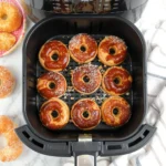 Vue rapprochée de donuts bien dorés et uniformes dans le panier d’une friteuse à air