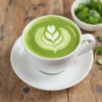 Tasse de matcha latte décorée d’un motif floral latte art sur table en bois