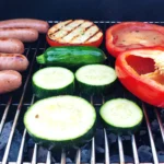 Poivrons, courgettes et tomates grillées au barbecue pour accompagner des saucisses