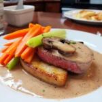 Blanquette de veau servie avec carottes fondantes, poireaux et champignons de Paris.