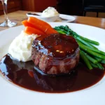 Tournedos de bœuf servi avec purée de pommes de terre, haricots verts et carottes glacées.